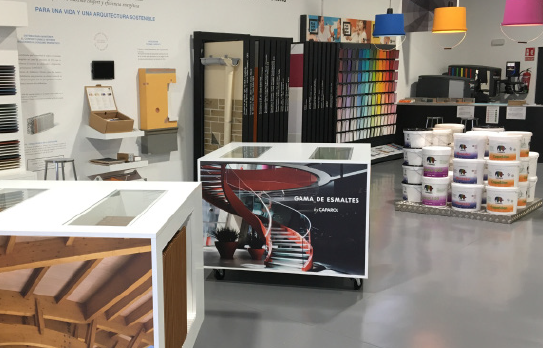 Muestra de un espacio de exhibición con una mesa blanca y una estructura de escalera roja en un entorno de diseño interior.